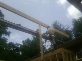 Carpenter setting a ridge beam over a new addition frame — Ice Dam Removal by Roofing Brothers in Waterbury