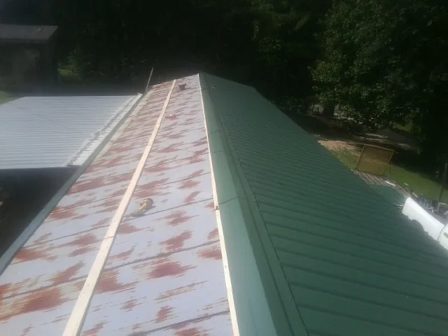 Old rusted panels beside newly installed green metal roofing — Wind Damage Roof Repair by Roofing Brothers in Waterbury