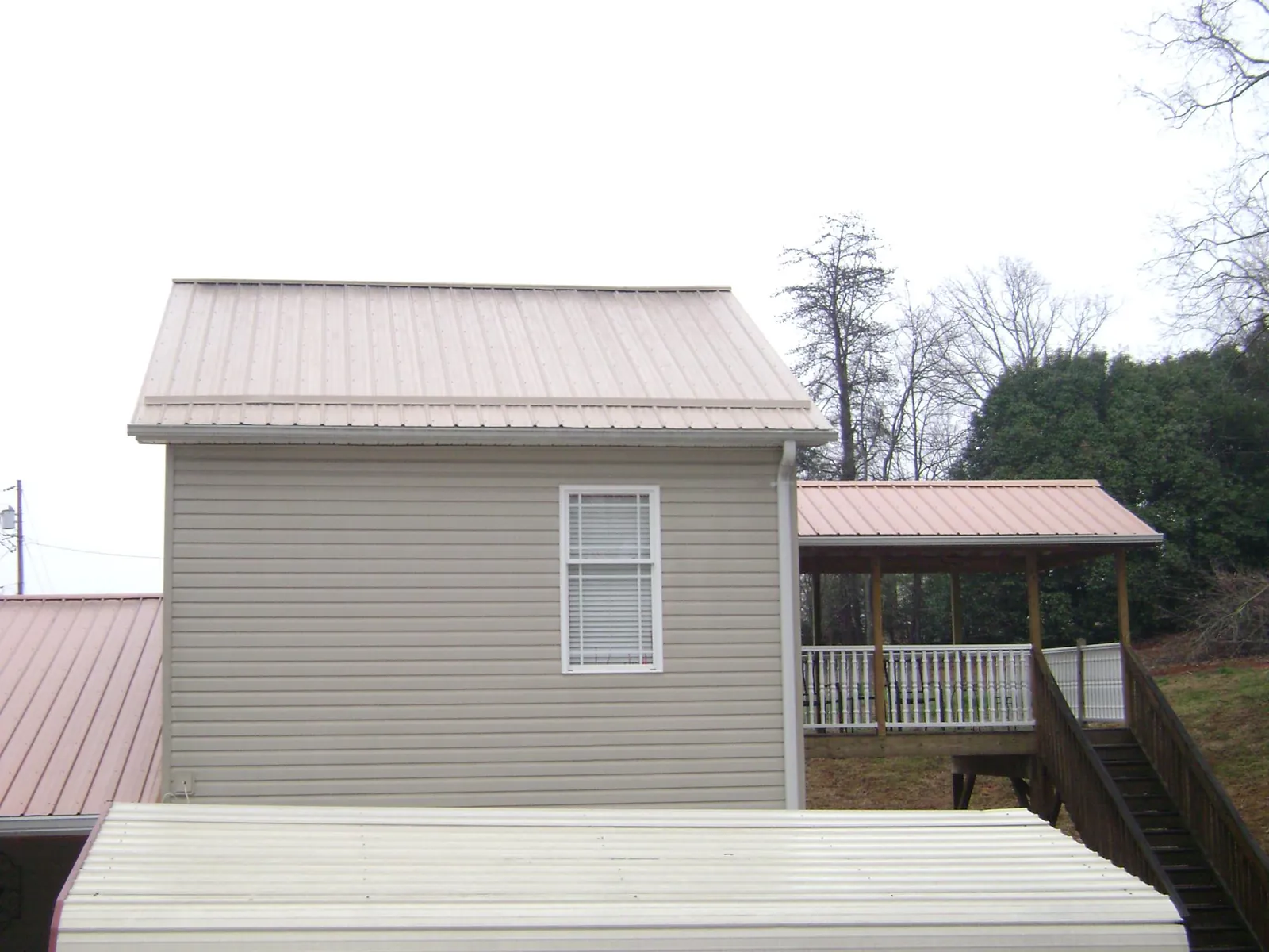 Tan metal roofs on a two story addition and attached porch, from a Roof Replacement job in Waterbury